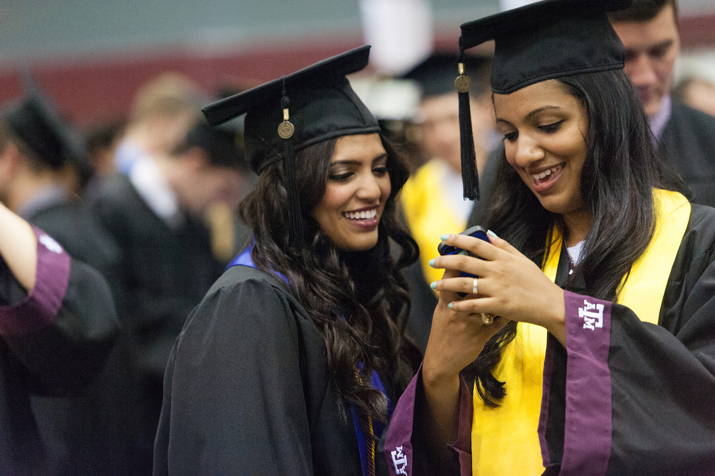 Two graduates looking at a phone