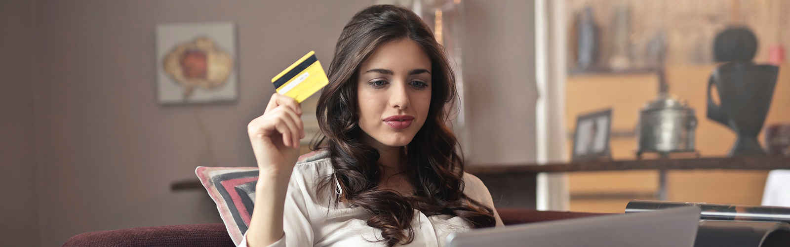 Image of a female students holding a payment card with a laptop computer in front of her.