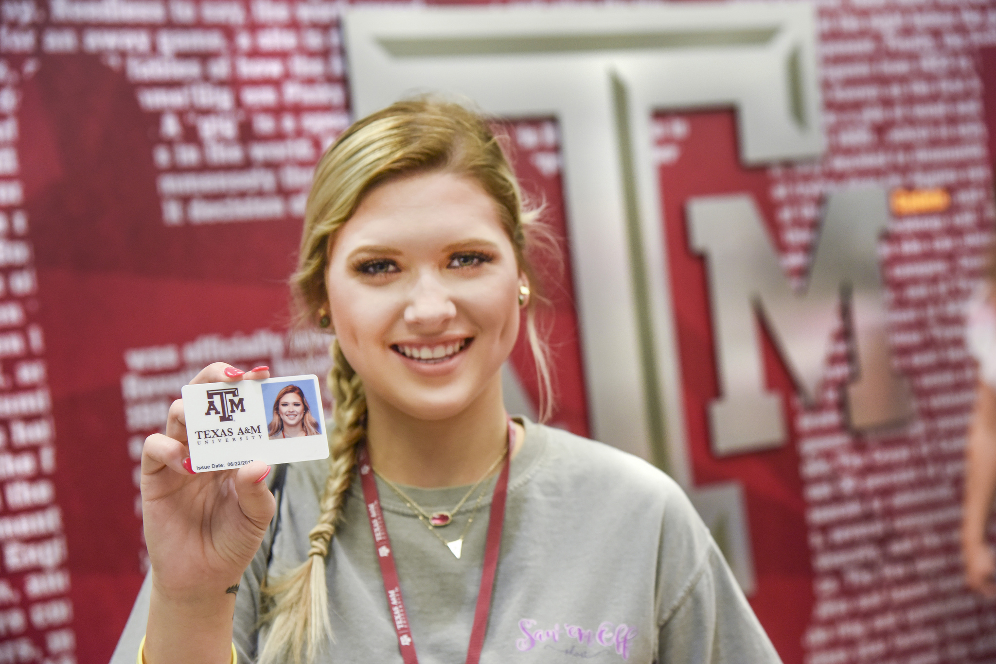 female student holding up an Aggie Card